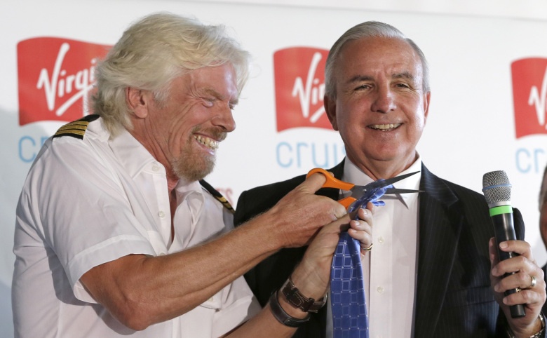 Richard Branson, founder of the Virgin Group, left, laughs as he cuts the tie of Miami-Dade County Mayor Carlos Gimenez, Tuesday, June 23, 2015, at Perez Art Museum in Miami, after a news conference where it was announced that Virgin Cruises will set sail from PortMiami in 2020. (AP Photo/Alan Diaz)